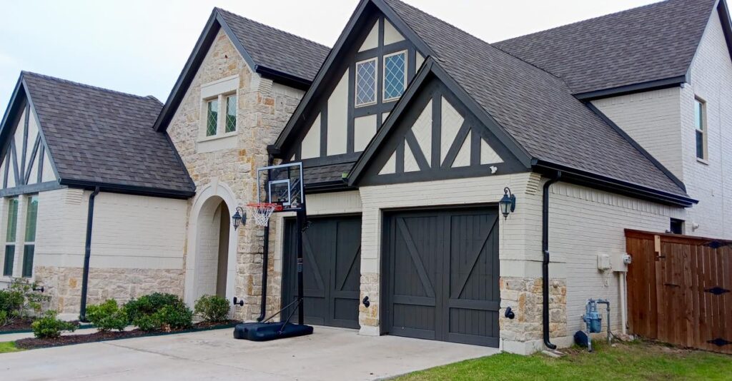 A house with two garage doors and a basketball hoop.