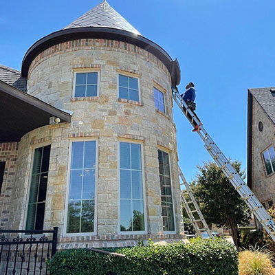 A man on a ladder cleaning the windows of a house.
