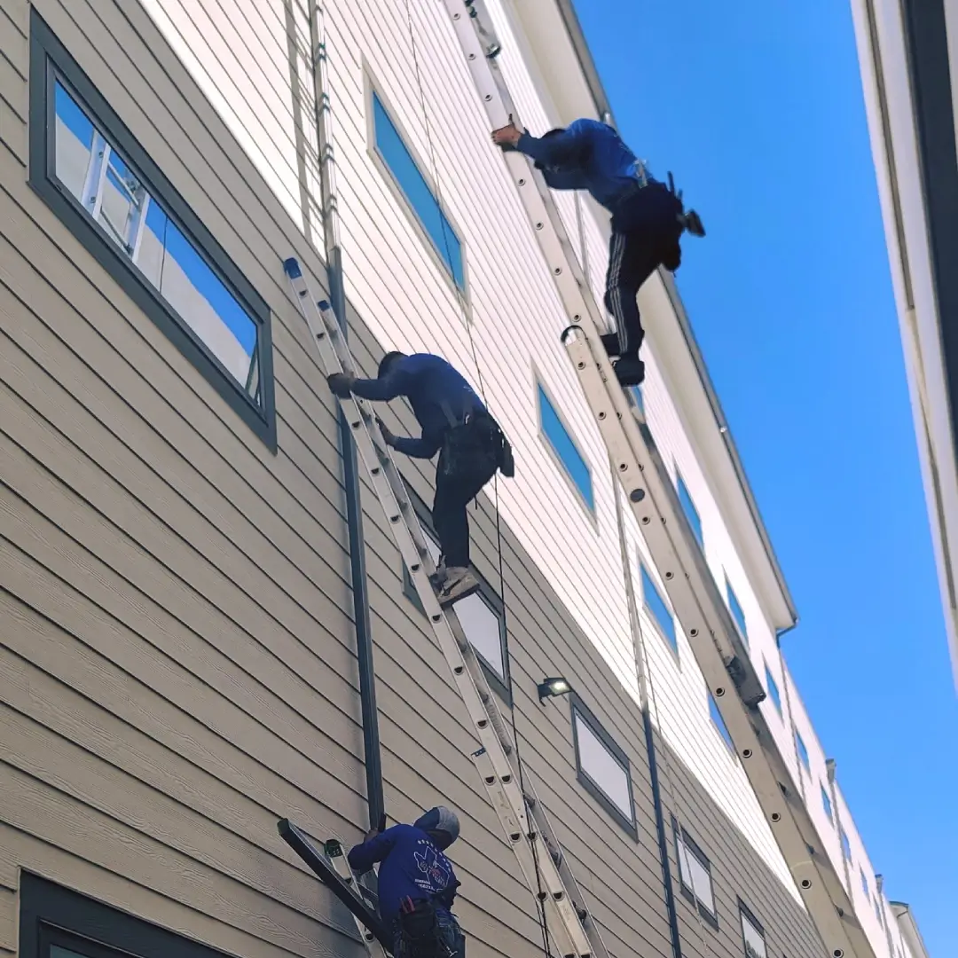 Three men climbing up a building on ropes.