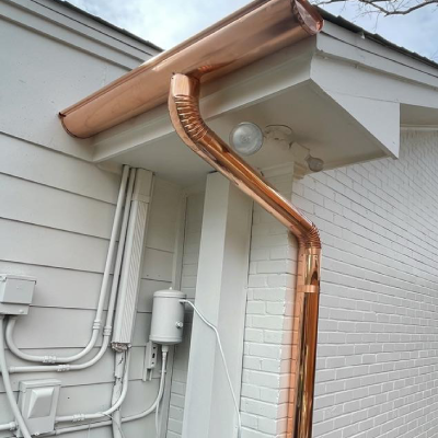 A copper gutter is attached to the side of a house.